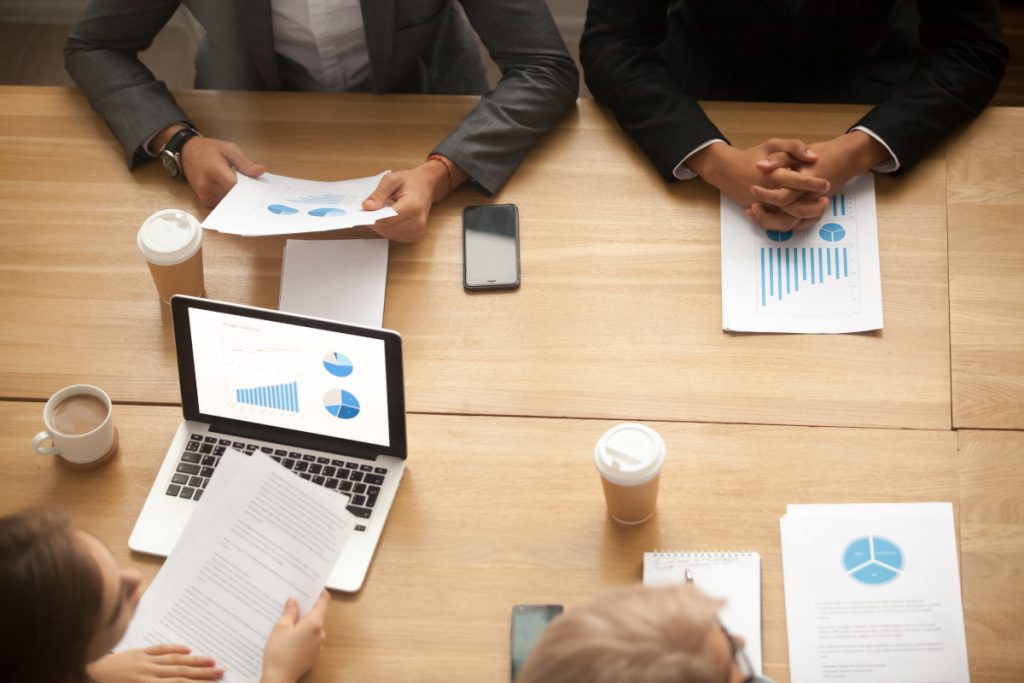 Business team brainstorm on new marketing plan analyzing statistics at group meeting, businesspeople working together on project report with financial results, teamwork concept, top view from above